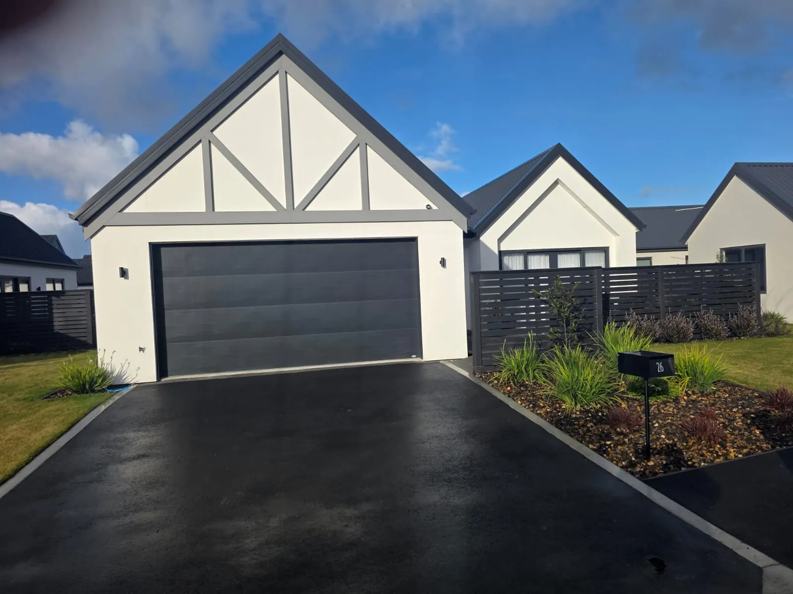 Completed gable home with white plaster, feature trim and charcoal garage door