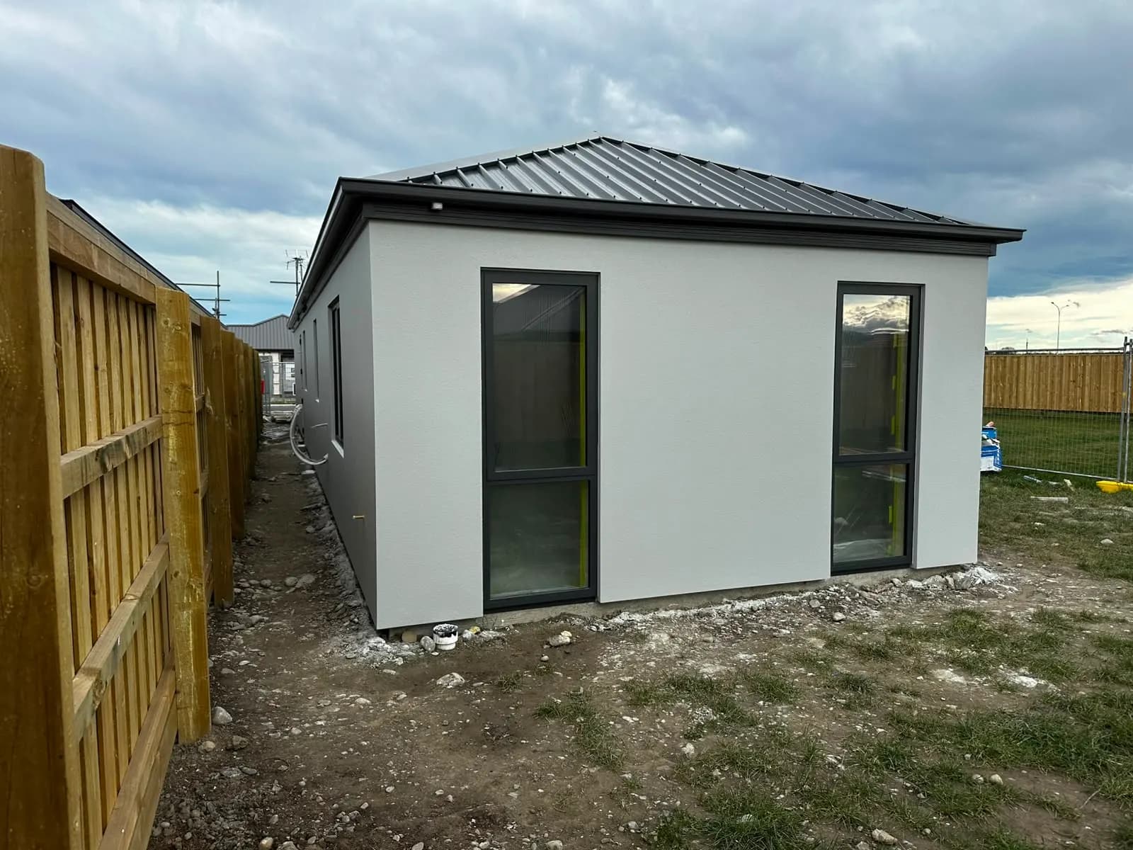 Completed single-storey home with light grey plaster and dark roof