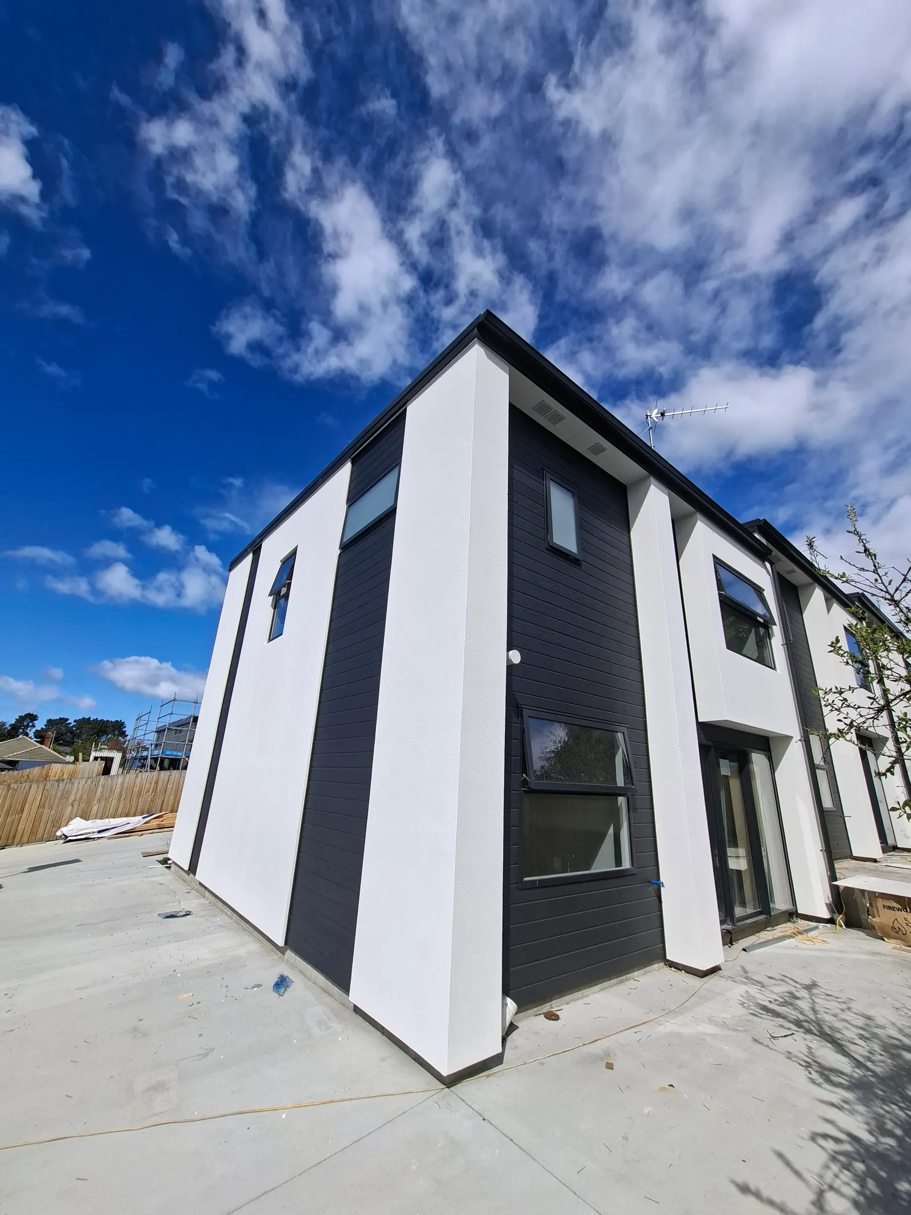 Two-storey townhouses in Canterbury with smooth white exterior plaster and dark cladding