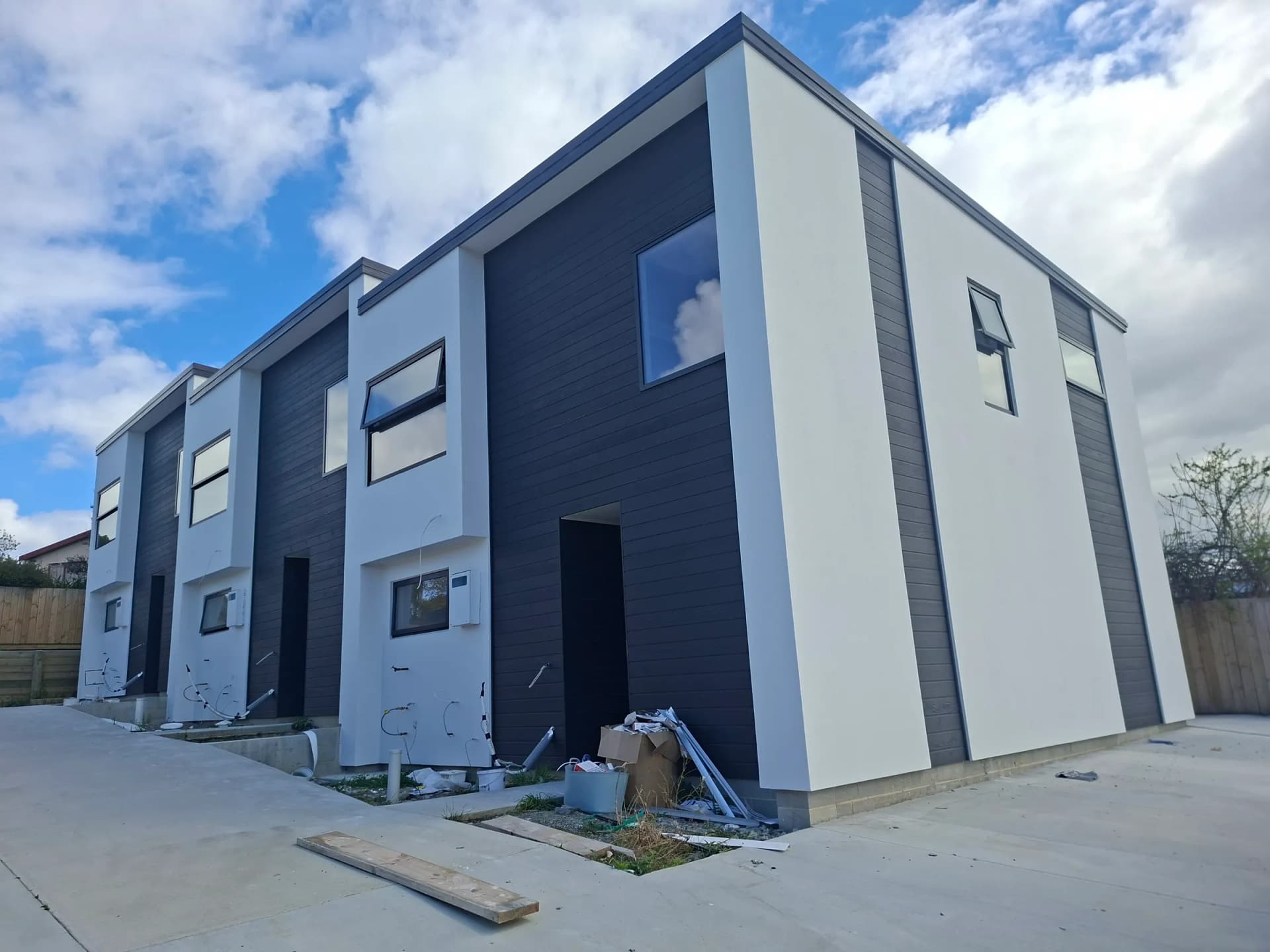 Row of new townhouses with white plaster finish and charcoal weatherboard accents