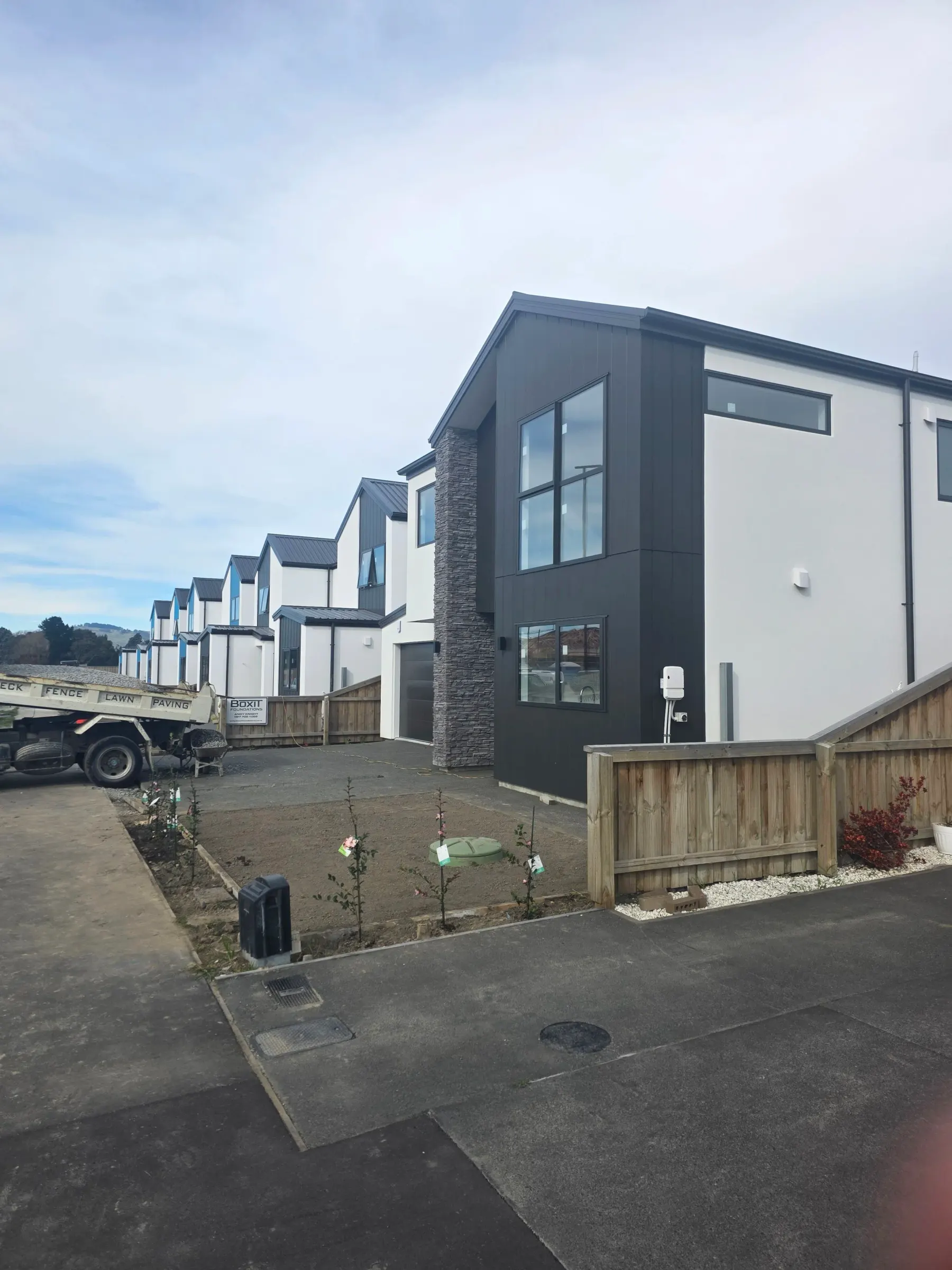 Two-storey home with white plaster, charcoal cladding and stone base