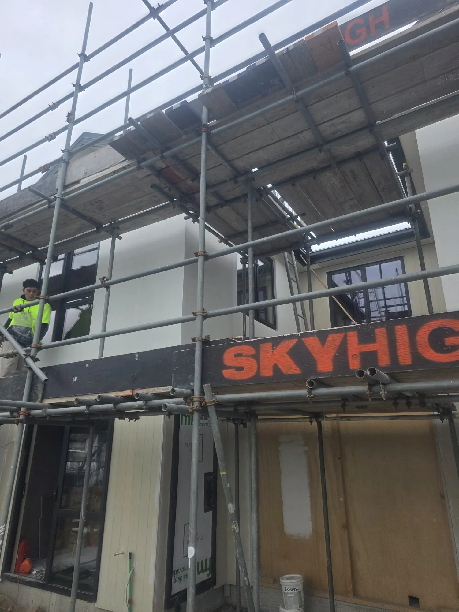 Two-storey homes under scaffolding during exterior plastering